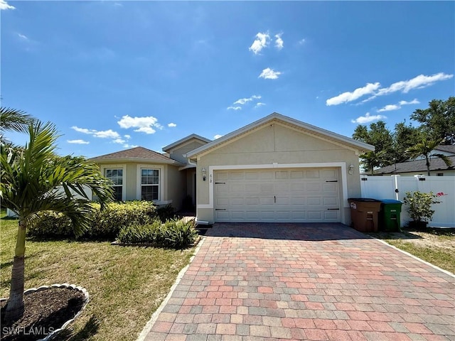 ranch-style home with an attached garage, fence, decorative driveway, and stucco siding