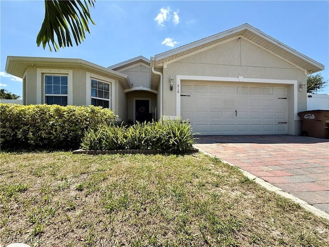 single story home featuring a garage, stucco siding, and decorative driveway