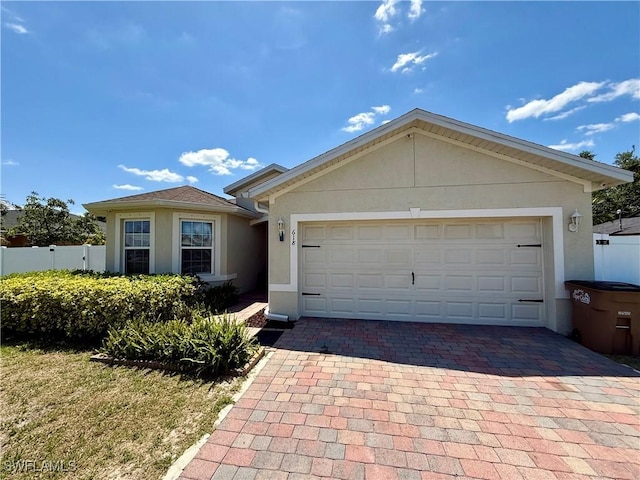 ranch-style home with a garage, stucco siding, fence, and decorative driveway