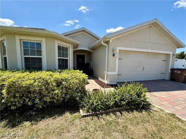 ranch-style home featuring an attached garage, driveway, and stucco siding