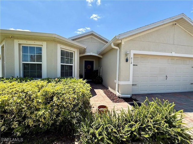doorway to property featuring driveway, a garage, and stucco siding