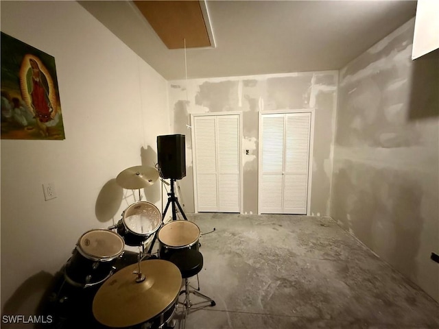 miscellaneous room with unfinished concrete flooring and attic access