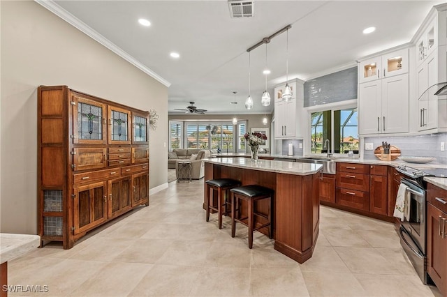 kitchen with crown molding, stainless steel electric range oven, a breakfast bar area, visible vents, and backsplash