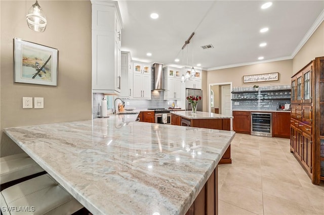 kitchen featuring wine cooler, a sink, visible vents, appliances with stainless steel finishes, and wall chimney exhaust hood