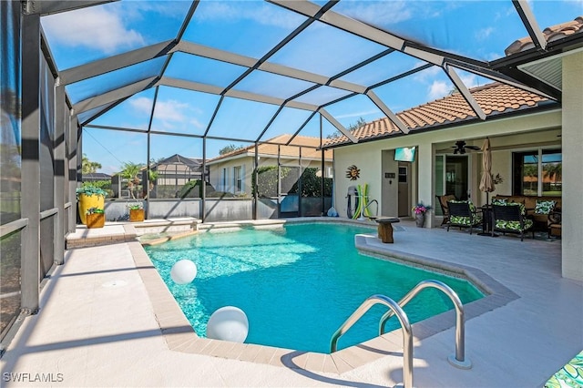 outdoor pool featuring glass enclosure, a jacuzzi, a ceiling fan, and a patio