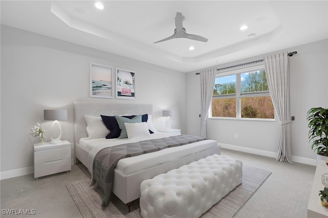 carpeted bedroom with ceiling fan, recessed lighting, a raised ceiling, and baseboards