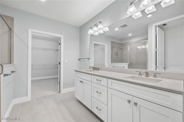 bathroom with a spacious closet, a sink, a shower stall, and double vanity