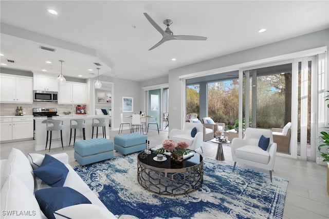 living room with a ceiling fan, visible vents, and recessed lighting