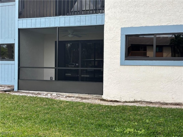 property entrance featuring a yard and stucco siding