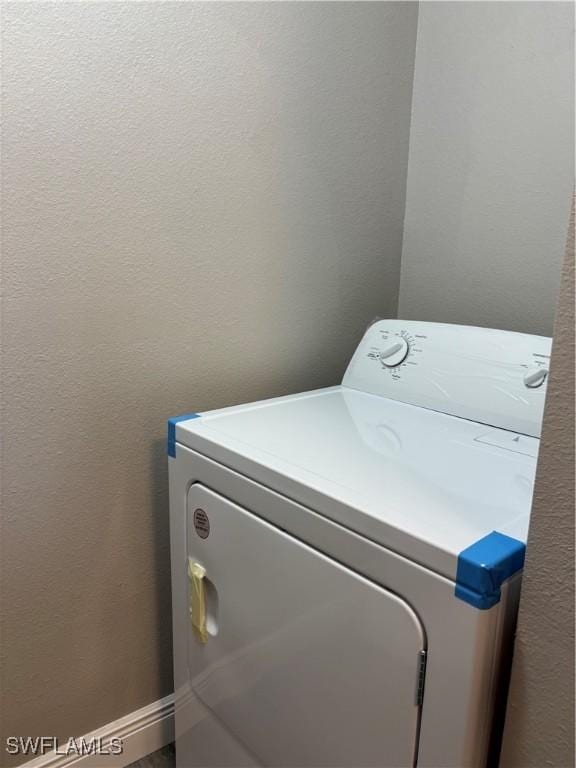 washroom with laundry area, washer / clothes dryer, and a textured wall