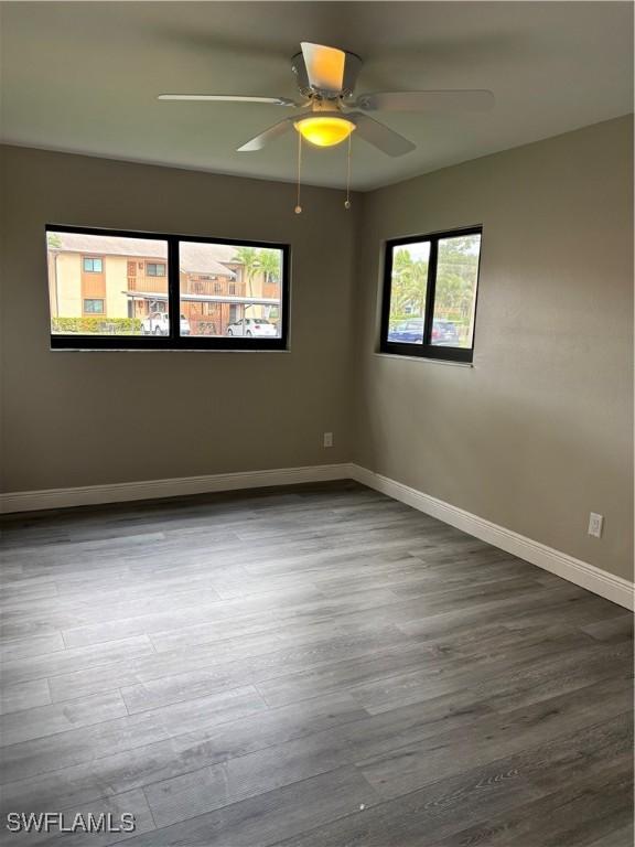 empty room with ceiling fan, baseboards, and wood finished floors