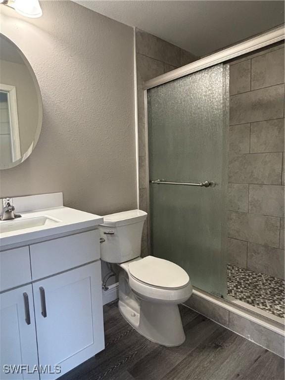 bathroom featuring toilet, wood finished floors, and a shower stall