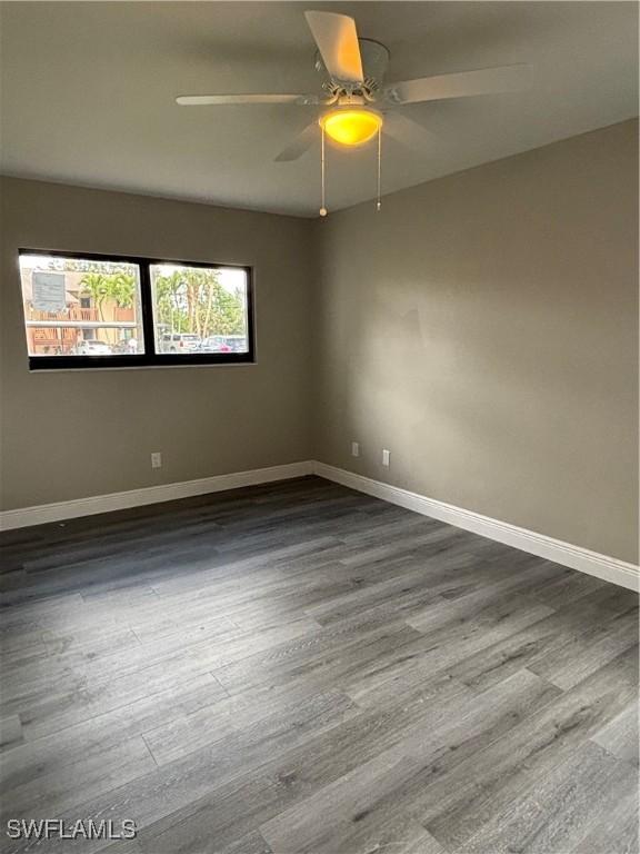 unfurnished room with dark wood finished floors, baseboards, and ceiling fan