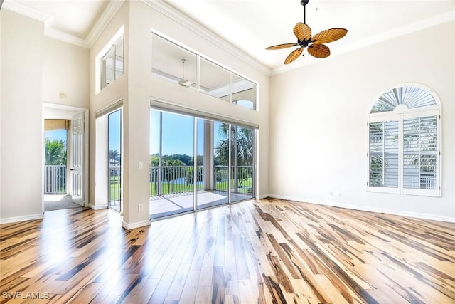 empty room with ornamental molding, wood finished floors, and baseboards