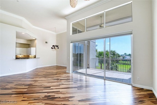 interior space with a notable chandelier, wood finished floors, baseboards, and ornamental molding