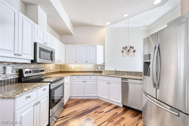 kitchen featuring a chandelier, white cabinets, backsplash, and stainless steel appliances