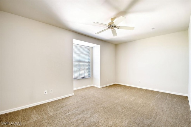 carpeted spare room featuring a ceiling fan and baseboards