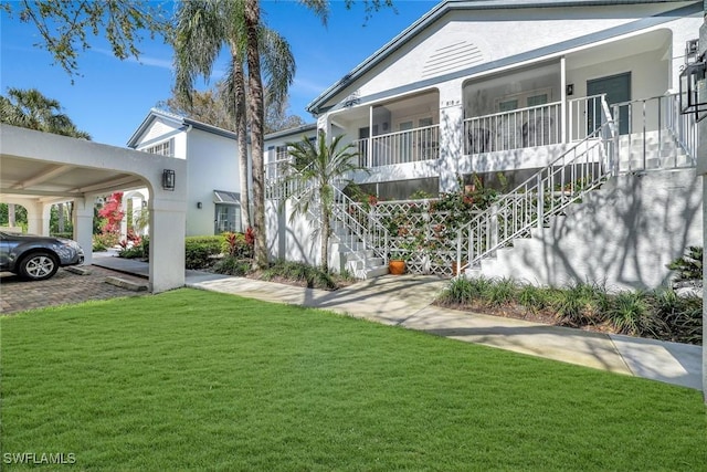 exterior space with stairs, a front yard, and stucco siding