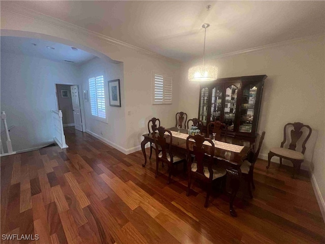 dining area featuring arched walkways, crown molding, baseboards, and wood finished floors