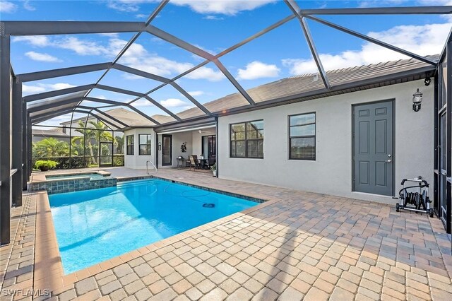 view of swimming pool featuring a patio, a pool with connected hot tub, and a lanai