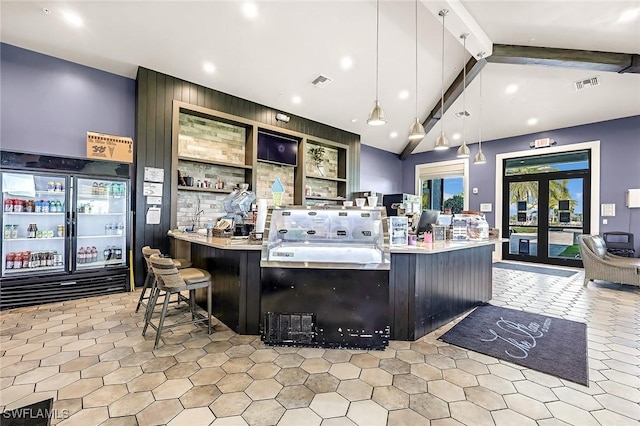 kitchen featuring hanging light fixtures, vaulted ceiling with beams, visible vents, and a kitchen bar
