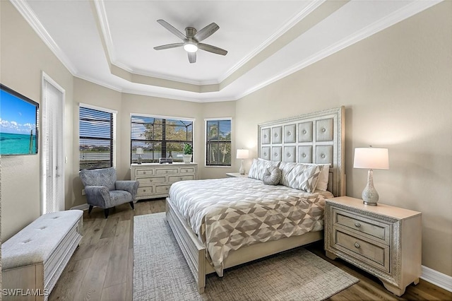 bedroom featuring a raised ceiling, wood finished floors, and ornamental molding