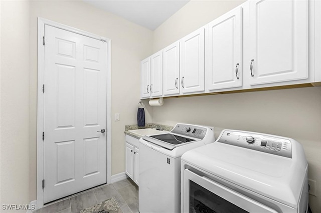 laundry room with baseboards, wood tiled floor, cabinet space, separate washer and dryer, and a sink