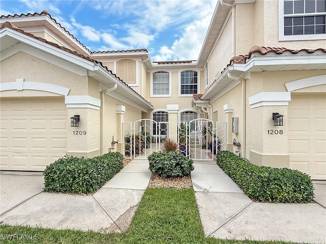 property entrance featuring a gate, a tiled roof, an attached garage, and stucco siding