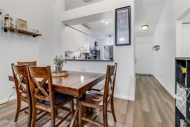 dining space featuring visible vents, light wood-style flooring, and baseboards