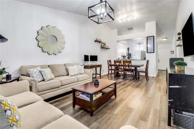 living room featuring a notable chandelier, baseboards, visible vents, and light wood-style floors