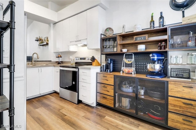 kitchen featuring under cabinet range hood, a sink, open shelves, and stainless steel electric stove