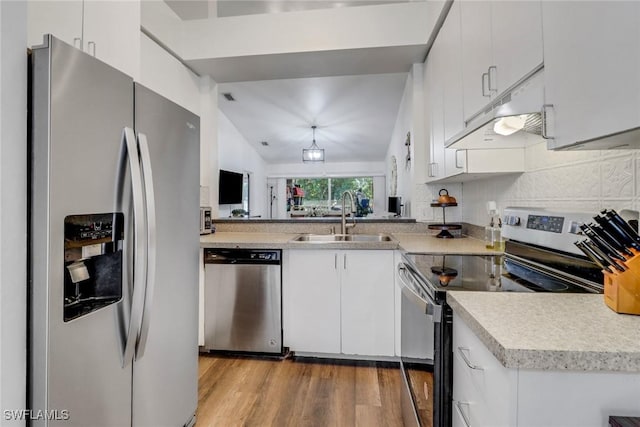 kitchen with white cabinets, appliances with stainless steel finishes, light countertops, under cabinet range hood, and a sink