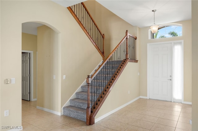 foyer with stairway, tile patterned flooring, arched walkways, and baseboards