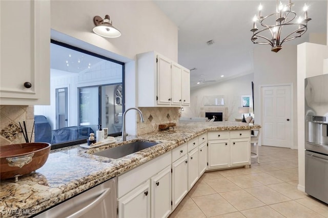 kitchen with a fireplace, light tile patterned floors, visible vents, vaulted ceiling, and a sink