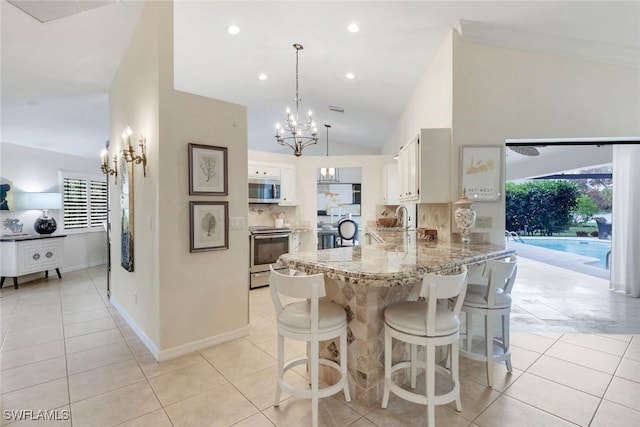 kitchen featuring stainless steel appliances, tasteful backsplash, light stone countertops, a chandelier, and a peninsula