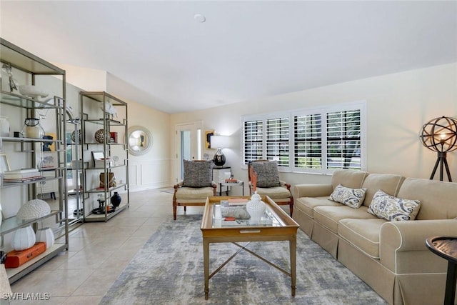 tiled living room featuring a decorative wall and wainscoting