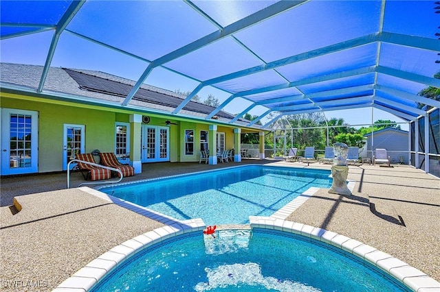 view of pool featuring a pool with connected hot tub, french doors, glass enclosure, and a patio