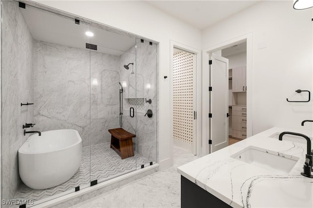 bathroom featuring a freestanding tub, a sink, marble finish floor, a marble finish shower, and double vanity