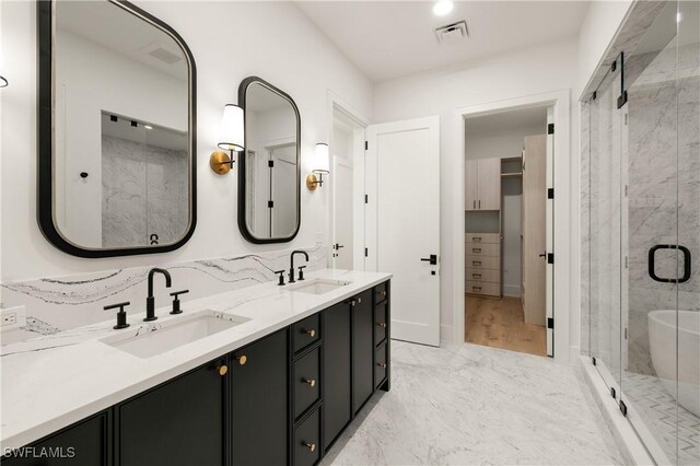 bathroom featuring marble finish floor, a sink, visible vents, and a shower stall