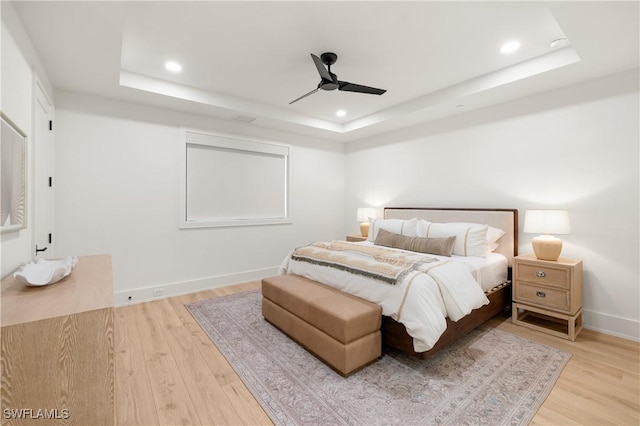 bedroom featuring a tray ceiling, light wood-style flooring, and recessed lighting