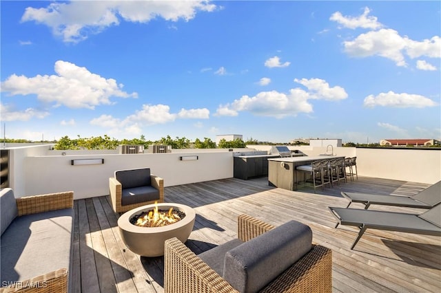 wooden deck featuring a fire pit, outdoor dry bar, and a sink