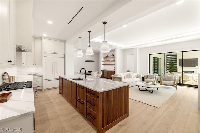 kitchen with paneled built in refrigerator, light wood-style floors, white cabinets, a sink, and modern cabinets