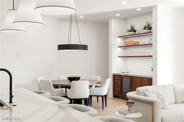 dining area with light wood-style flooring, wet bar, beverage cooler, and recessed lighting