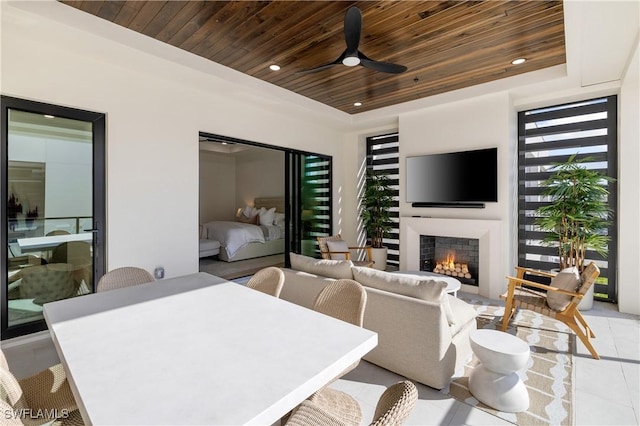 view of patio with outdoor dining area, ceiling fan, and an outdoor living space with a fireplace