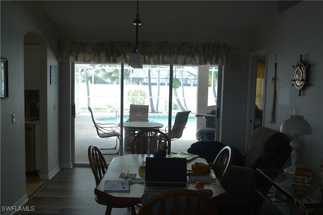 dining room featuring arched walkways, baseboards, a healthy amount of sunlight, and light wood finished floors