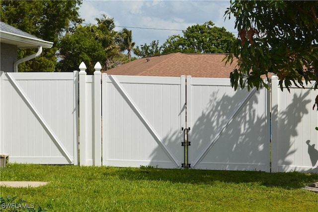 view of gate featuring fence and a lawn