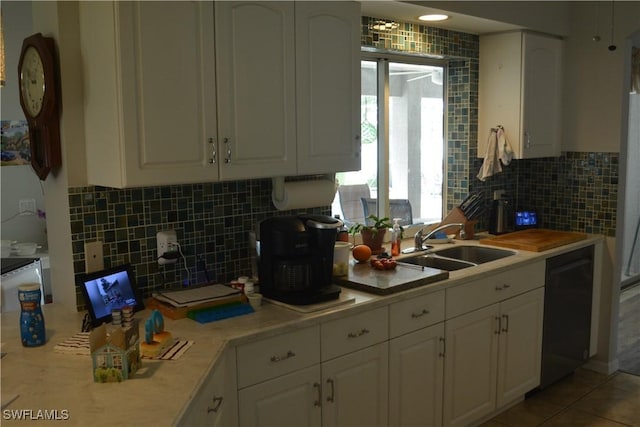 kitchen featuring black dishwasher, white cabinets, a sink, and light countertops