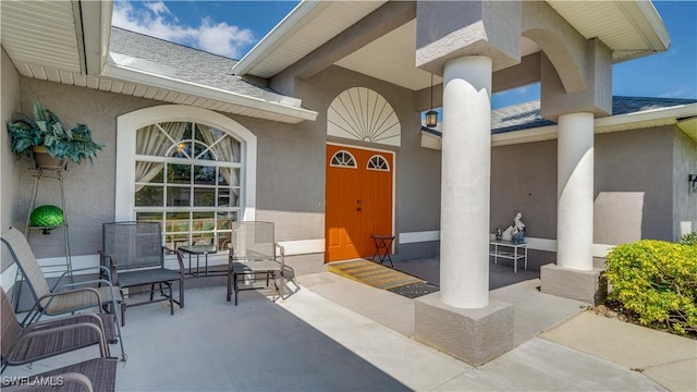 property entrance featuring a shingled roof and stucco siding