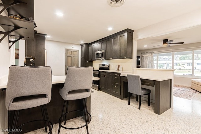 kitchen featuring visible vents, a peninsula, stainless steel appliances, a kitchen bar, and recessed lighting