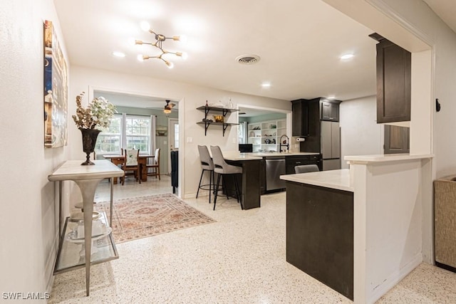 kitchen featuring a breakfast bar area, stainless steel appliances, light countertops, visible vents, and a peninsula